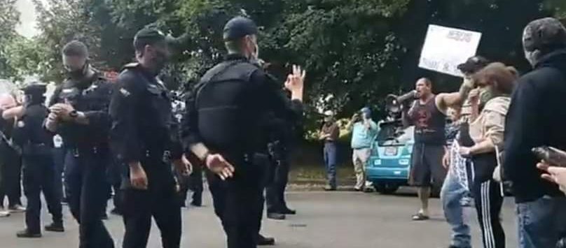 A screenshot of the Oregon trooper throwing a white power symbol.