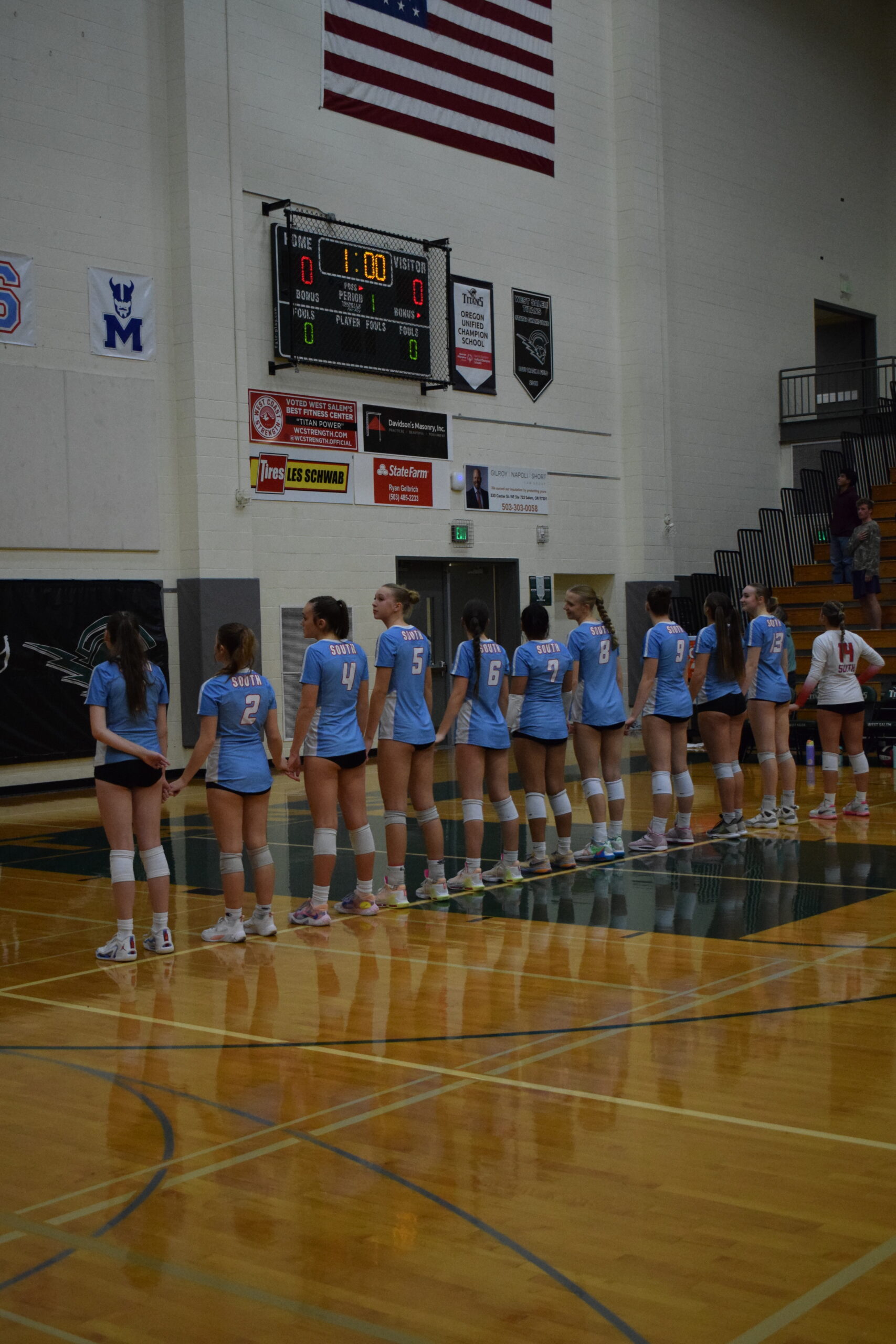 South Salem High School's varsity girls volleyball team stands in a line at the end of the court.
