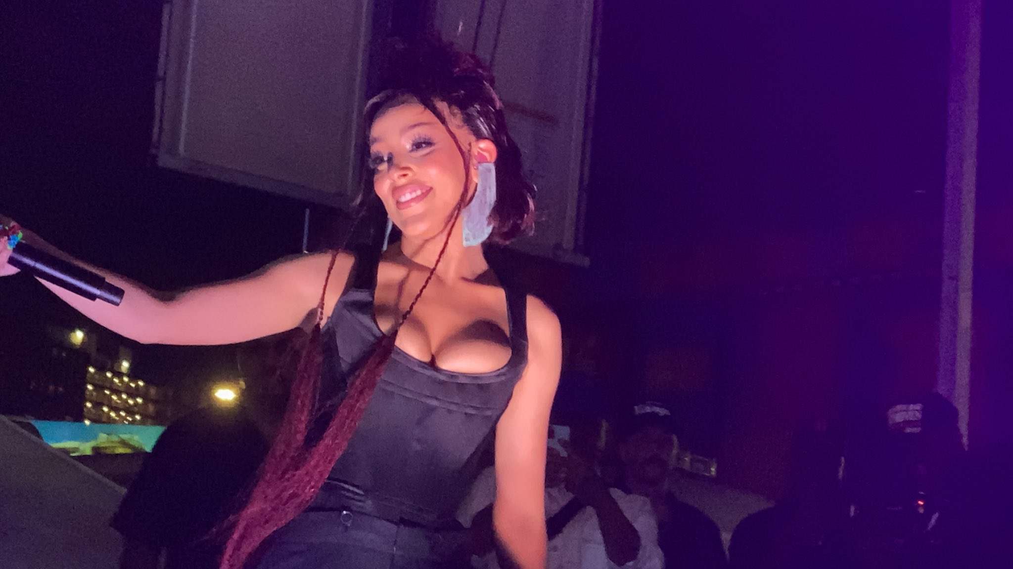Artist Doja Cat is on stage performing a song with a microphone in her hand.