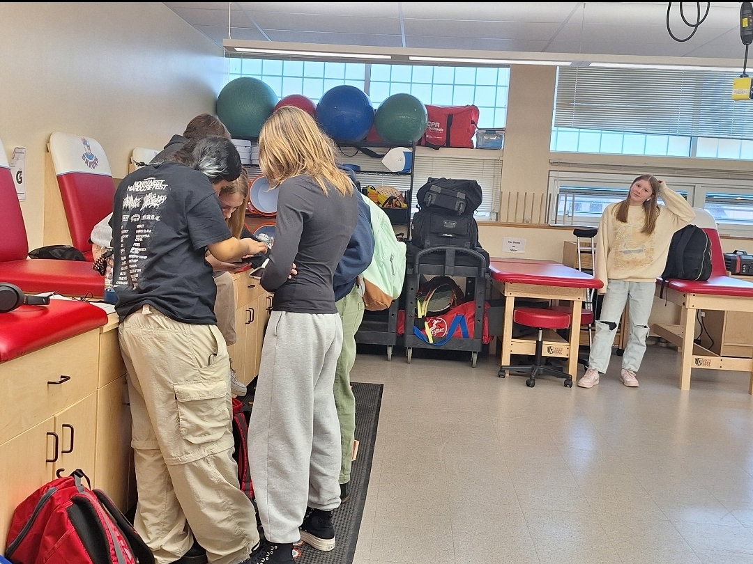 After school, several students practice their skills learned from class, properly taping a student's ankle.