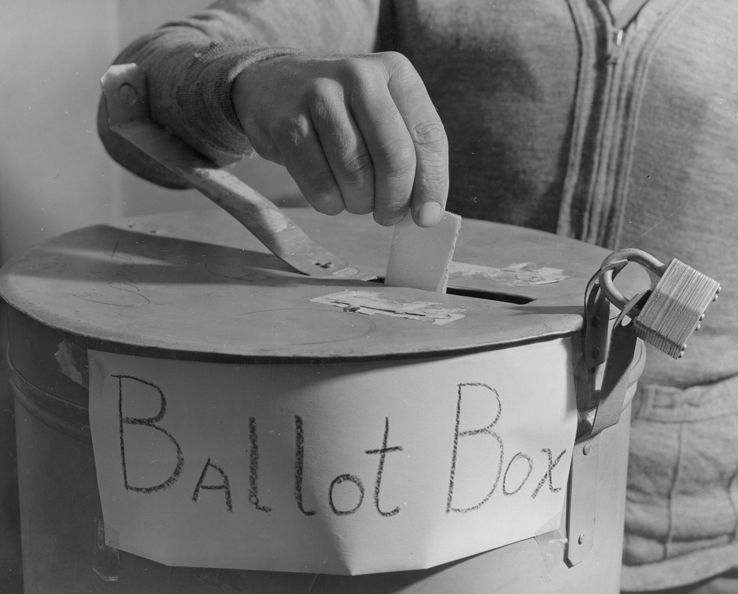 A man putting a ballot into a ballot box.