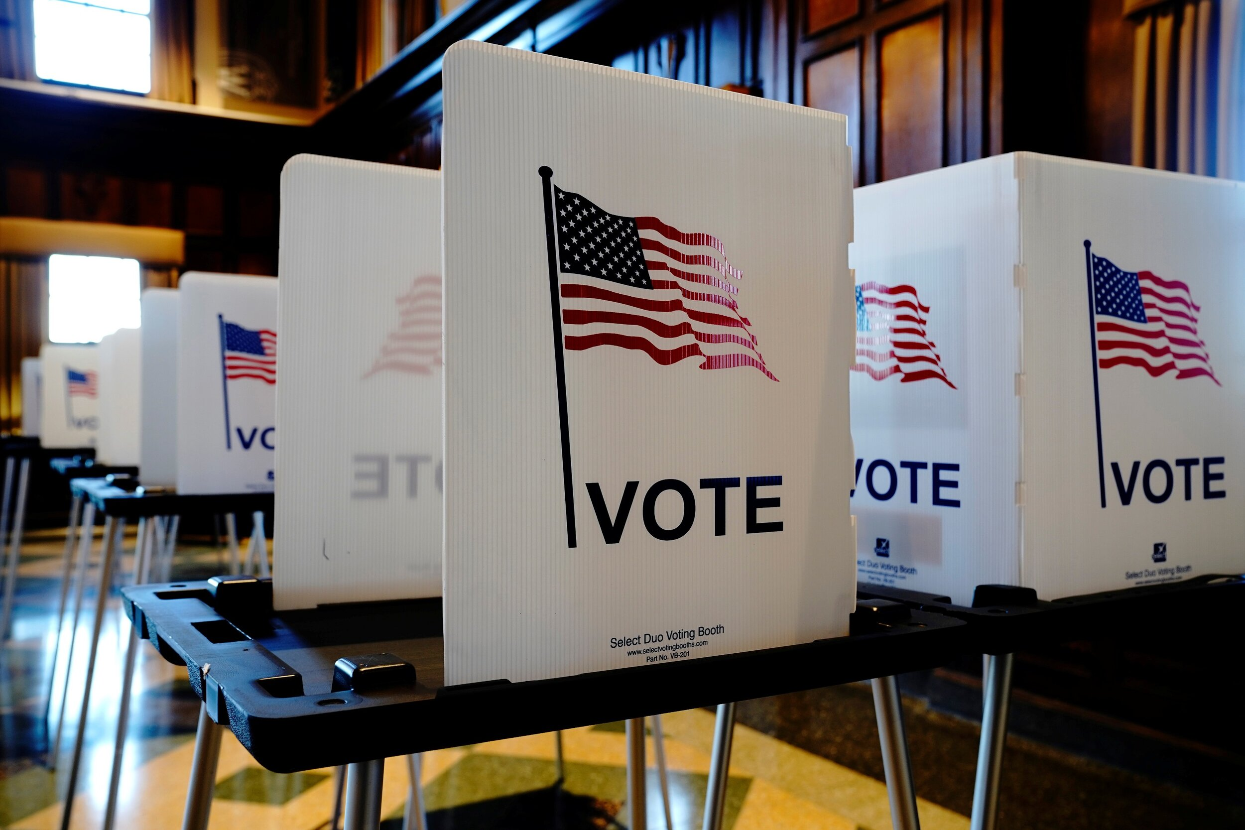 Voting booth dividers set up across a myriad of desks within a monitored area.