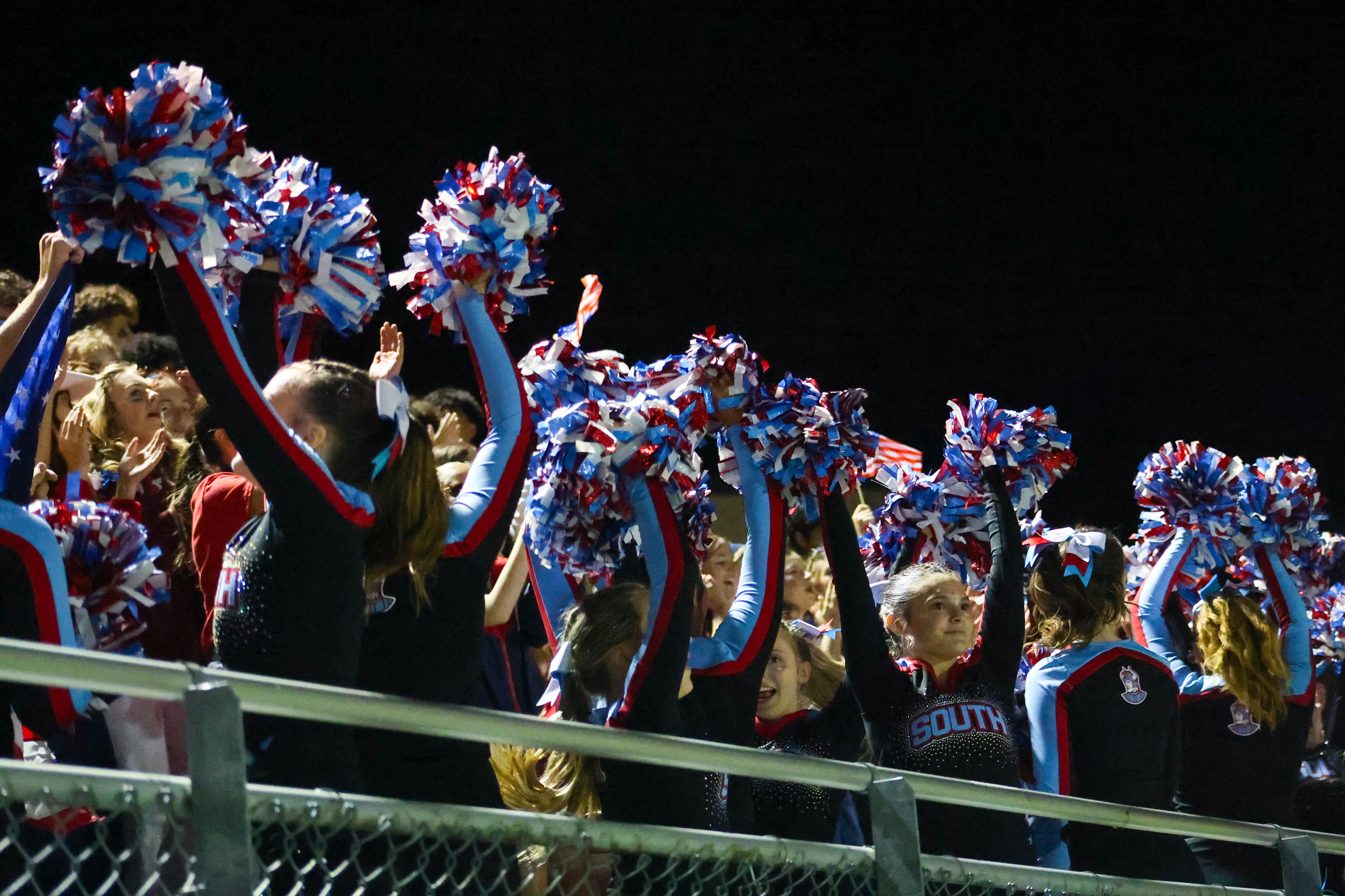 Saxon cheerleaders lead a crowd at a football game.